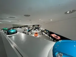 Sleek turquoise and blue sports cars displayed in a modern, brightly lit showroom, with a camera luminance meter