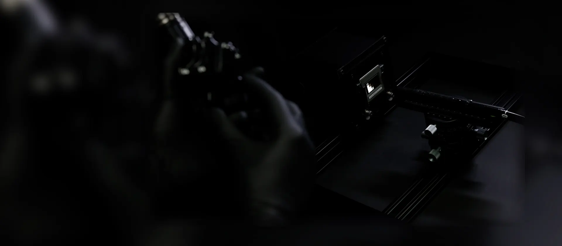 A dark, high-contrast shot of medical image quality testing equipment, including a test chart, with a hand adjusting a part