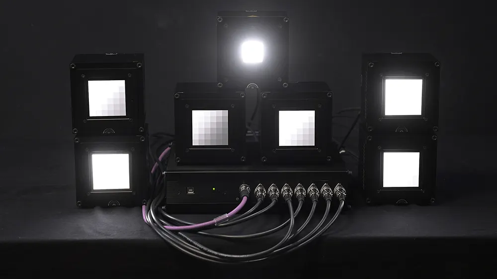 A setup of image quality blog analysis equipment including light sources and monitors displaying patterns, connected by cables