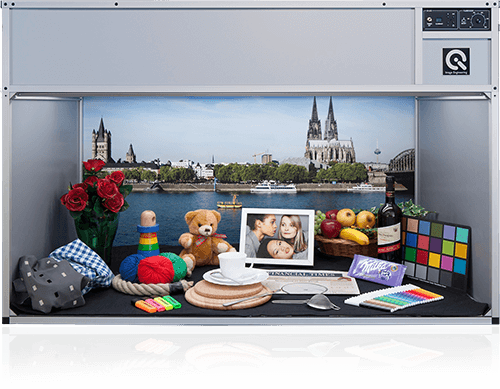 A light booth showcasing various objects, a color checker, and a backdrop of the Cologne Cathedral